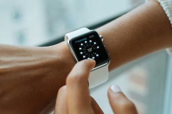 Osoba používající Apple Watch s bílým řemínkem při kontrole počasí na obrazovce. Detail dotykového ovládání na chytrých hodinkách od společnosti Apple. Ideální pro články o opravách dotykových obrazovek Apple Watch a příslušenství.