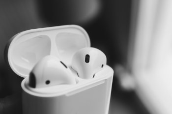 AirPods v otevřeném nabíjecím pouzdře – elegantní design Apple s dlouhou výdrží baterie a jednoduchým připojením k iPhonu, iPadu a dalším zařízením.